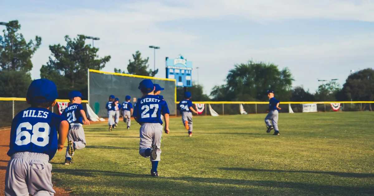 A few youth baseball players running on the field during a game