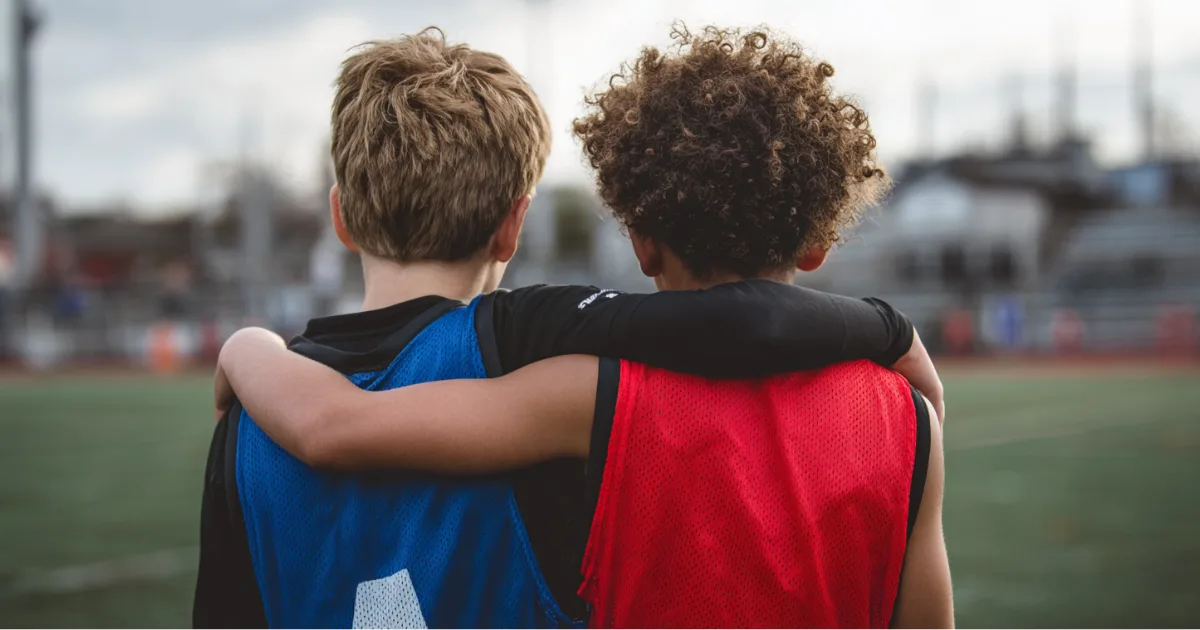 Two youth sport athletes with their arms around each other's back