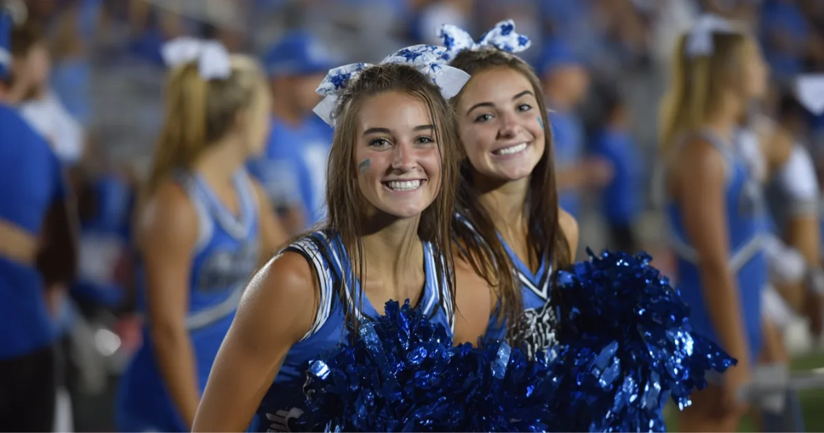 A high school cheerleader cheering during a football game