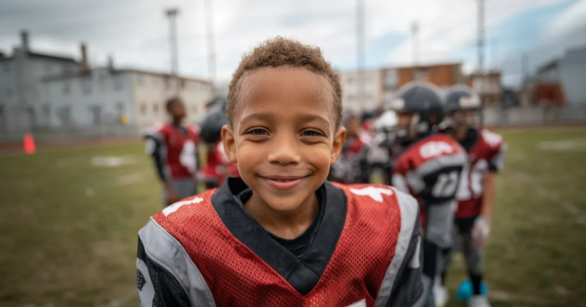 A youth football player smiling at the camera after a game