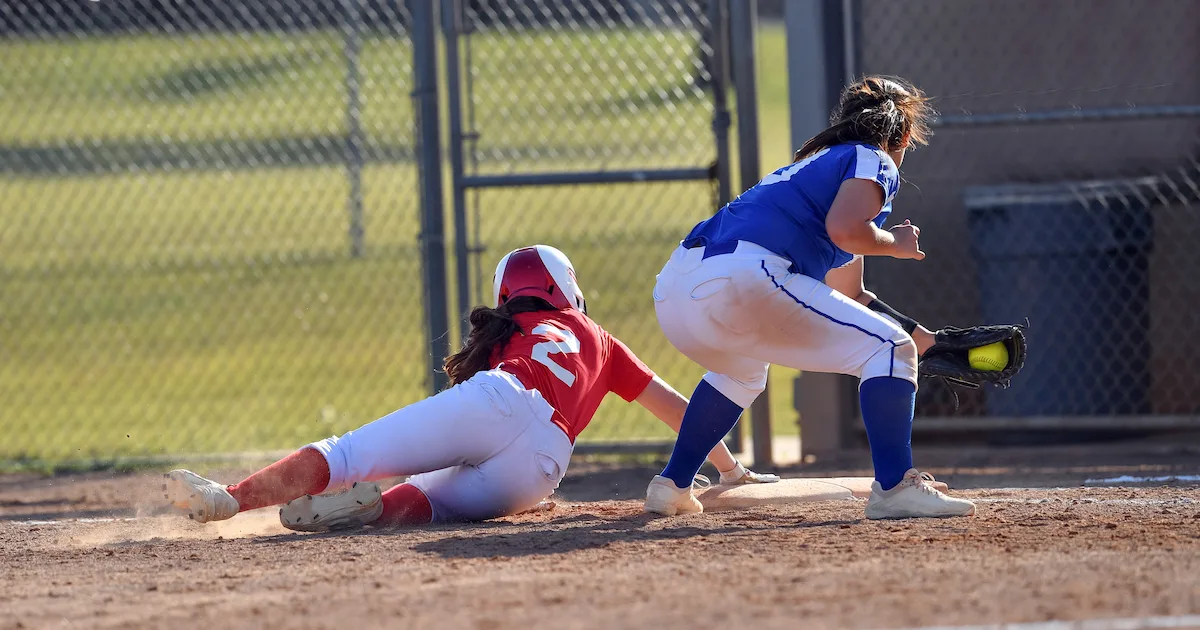 a softball player sliding safely back to first base