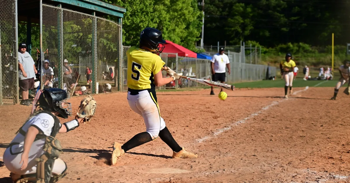 A youth softball player swinging at a ball during a game
