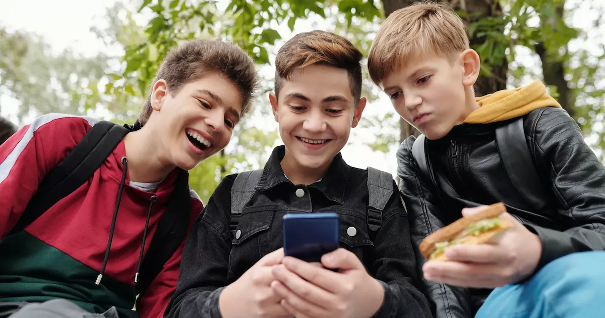 three young athletes viewing a youth sports website on a mobile device