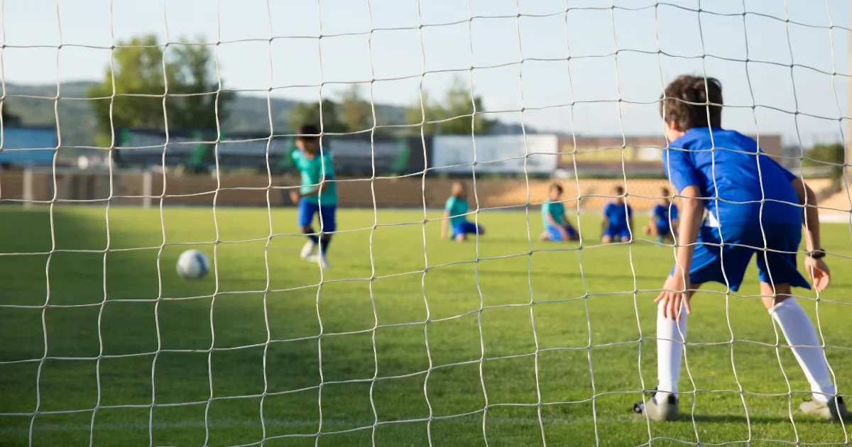 A youth soccer goalie positioned in front of the net during a game