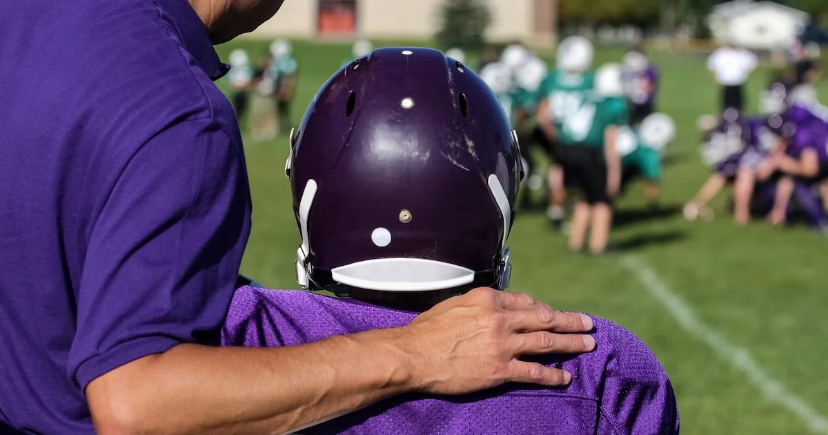 a youth sports coach helping an athlete from the sideline