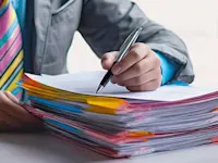 Person writing on a stack of business documents