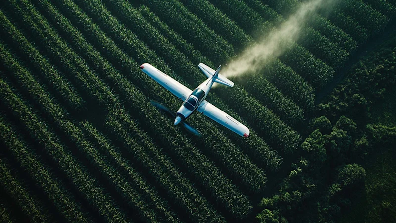 Airplane spraying pesticide on crop fields