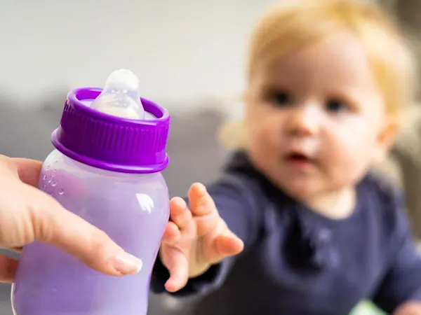 Baby being handed a bottle