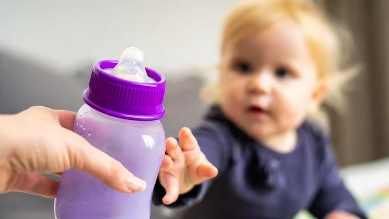 Baby being handed a bottle