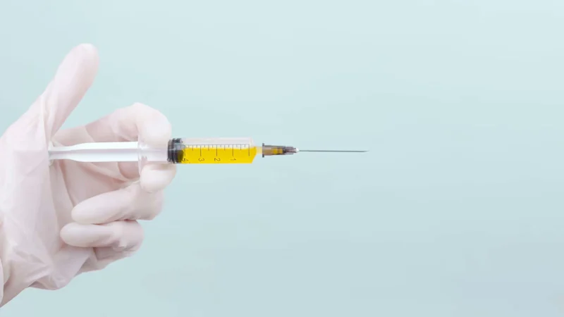 Gloved hand holding a syringe