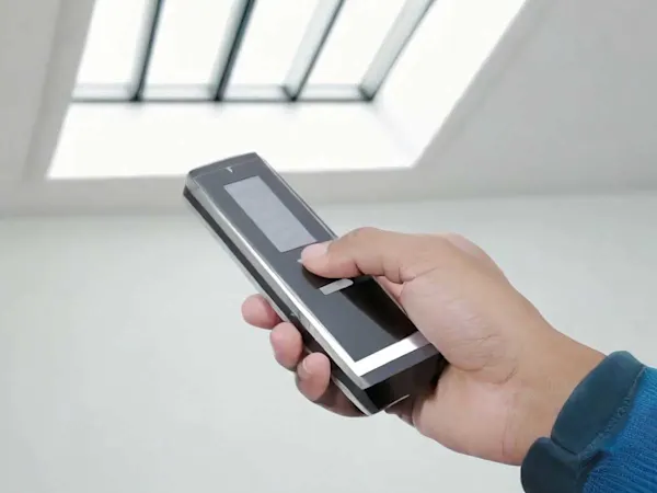 Hand holding a remote for an electric window on the roof