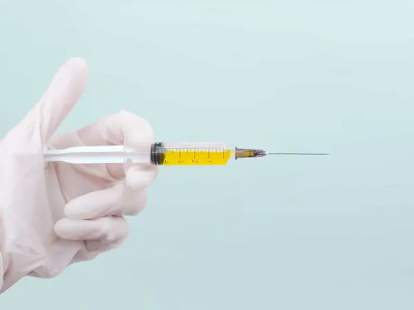 Gloved hand holding a syringe