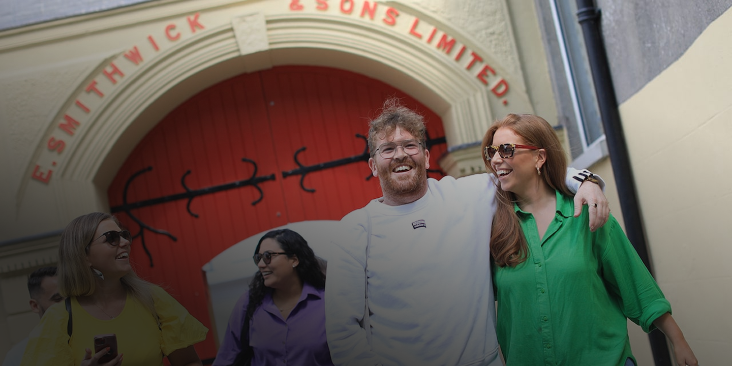 Group of people walking and smiling in front of a building with red doors.