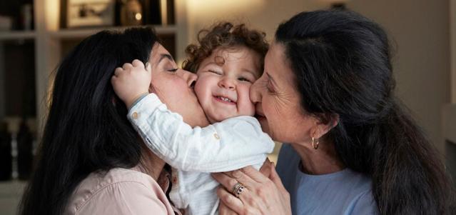 mom and grandma kissing child