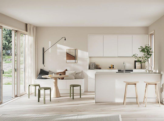 Lyst, åpent kjøkken-stue med hvite skap, eikegulv, grønne krakker og store glassdører.