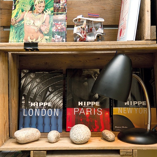 Trehylle med svart lampe, dekorsteiner, miniatyr tuk-tuk og bøker om London, Paris og New York.