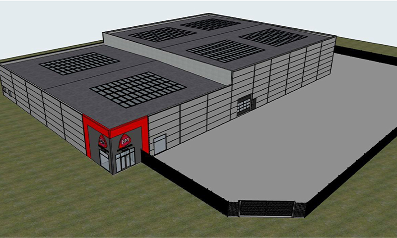 3D-modell av grå lagerhall med takvinduer, rød inngangsportal, gress og inngjerdet gårdsplass