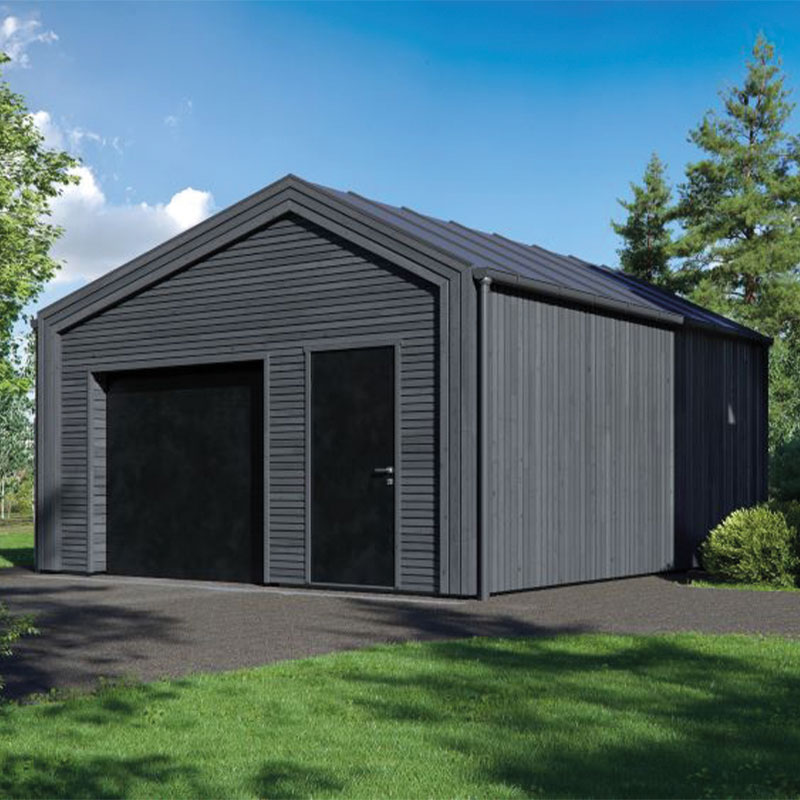 Mørk grå frittliggende garasje med svart port og dør, gressplen, trær og blå himmel.