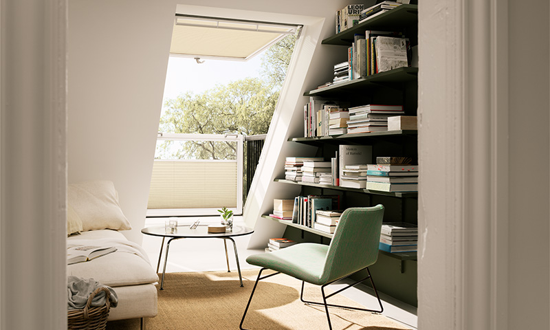 Lys lesekrok på loft med grønn stol, rundt bord, beige sofa og mørkegrønn bokhylle ved vindu