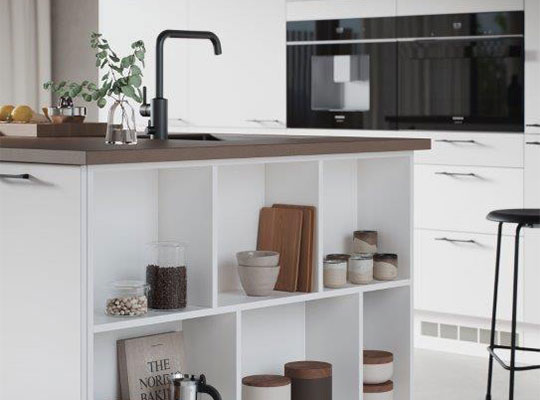 Hvit kjøkkenøy med mørk bordplate, svart armatur, åpne hyller med glasskrukker og trebrett