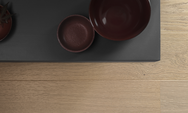 Toppbilde av mørkt brett med røde keramikkboller og liten plante på lyst trebord.