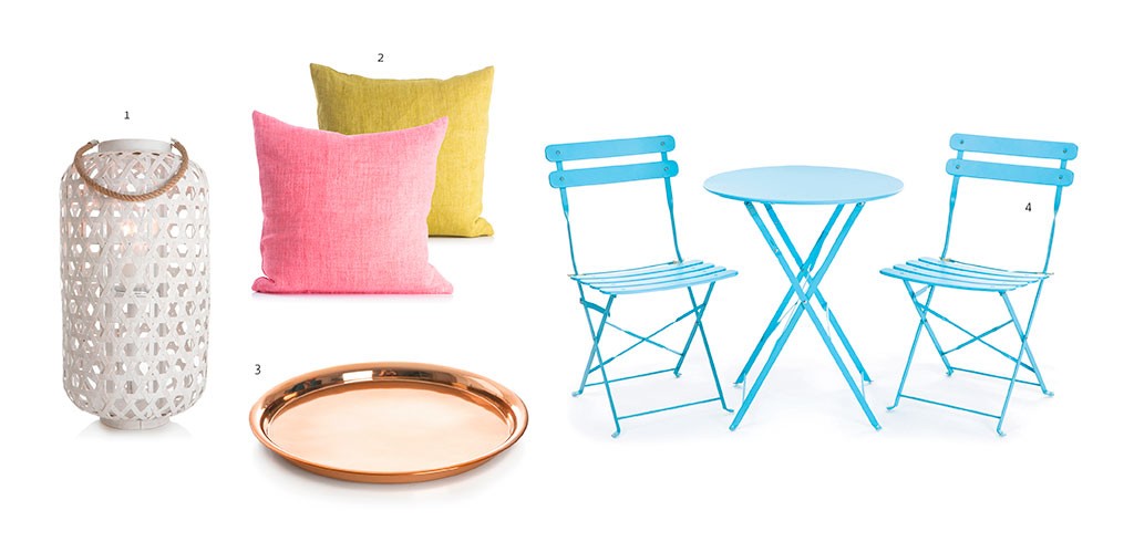 Hvit flettet lanterne, rosa og gul puter, kobberfat og lyseblå kafébord med to stoler.