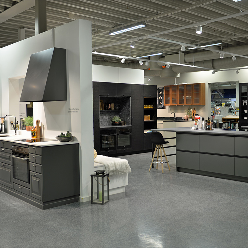 Moderne kjøkkenutstilling med mørkegrå skap, hvite benkeplater og åpent industriloft