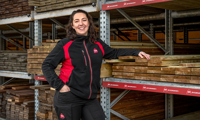 smilende ansatt i byggmakker på trelasten