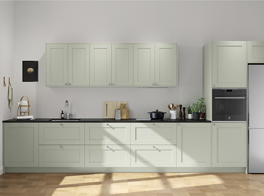 Lyst kjøkken med salviegrønne skap, svart benkeplate, lys parkett, urtepott og kokekar