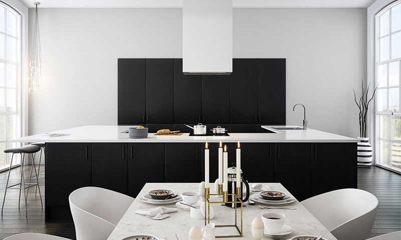 Moderne kjøkken med svarte skap, hvit øy og spisebord dekket med frokostservise og tente lys.