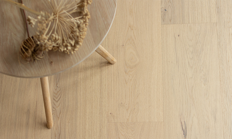 Lite rundt bord i lyst tre med tørkede blomster på lyse eikegulv.