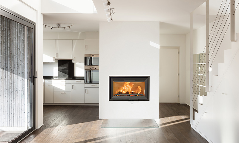 Moderne lyst rom med mørkt gulv, innebygd svart peis, hvit kjøkkeninnredning og trapp