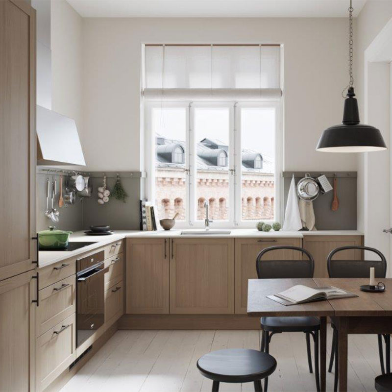 Lyst skandinavisk kjøkken med lyse tremøbler, hvite vegger, svart pendellampe og byutsikt.
