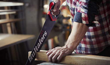 Snekker i rød-hvit rutete skjorte sager lyst tre med svart/rødt Hultafors-sag i verksted