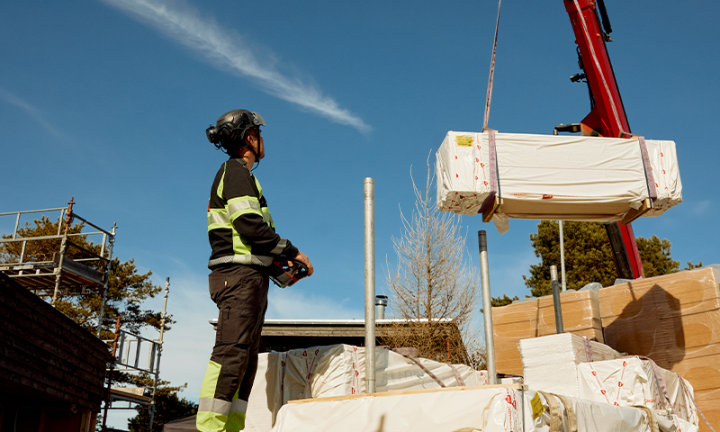 mann og kranbil som leverer byggevarer