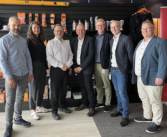 Syv mennesker foran vegg med produkter