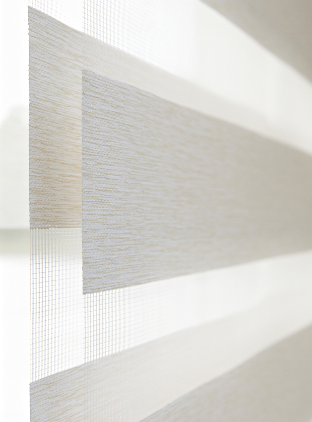 Nærbilde av hvit-beige rullegardin med vekslende tette og transparente striper.