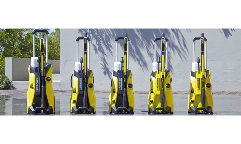 Fem gule og svarte Kärcher-høytrykksspylere på våt terrasse foran grå murvegg.