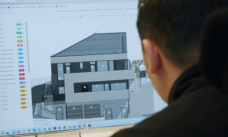 Mann sett bakfra foran skjerm med grå CAD-3D-modell av moderne boligbygning og fargede menyer