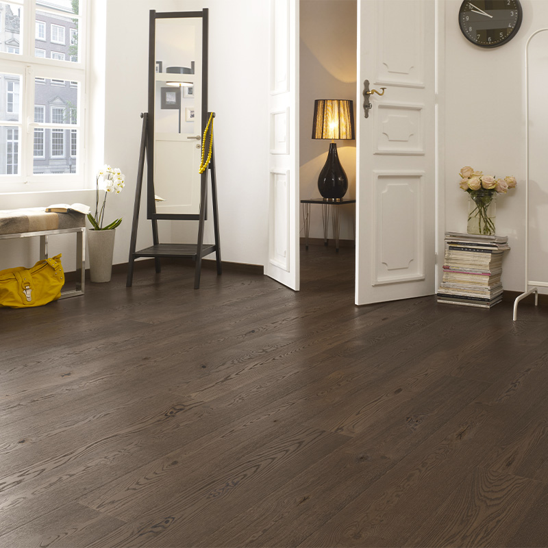 Hvitt rom med mørk eikeparkett, svart speilstativ, gul veske, åpen dobbeltdør til lunt interiør.