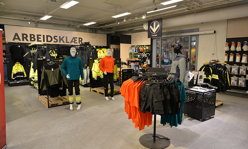 Butikkinteriør med mannequiner i gule og oransje varselklær under skiltet “Arbeidsklær”.