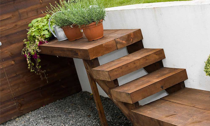 Brun tretrapp ved hvit vegg med terrakottakrukker med lavendel og vannkanne