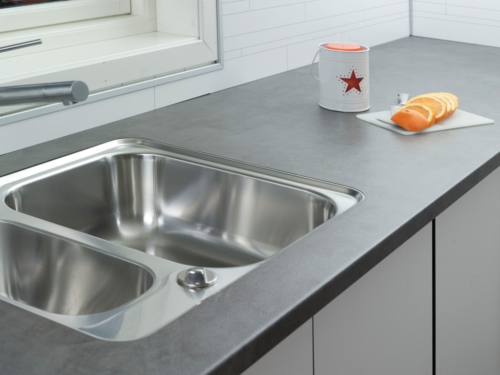 Grå benkeplate med dobbel rustfri stålvask, hvit boks med rød stjerne og skivet appelsin.