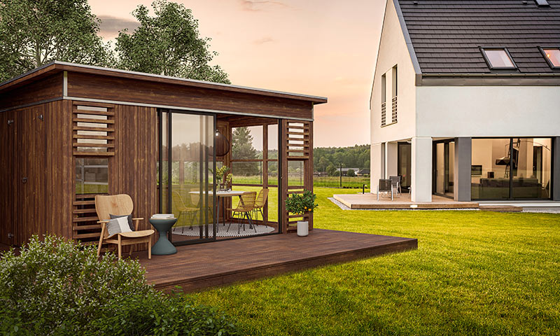 Moderne hvitt hus med trepaviljong, sitteplass på terrasse og grønn gressplen i solnedgang.