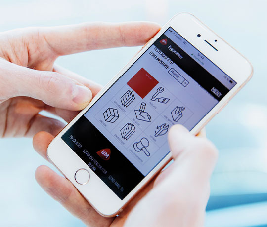 Hender holder hvit telefon med appskjerm: svarte linjeikoner for logistikk og rødt felt
