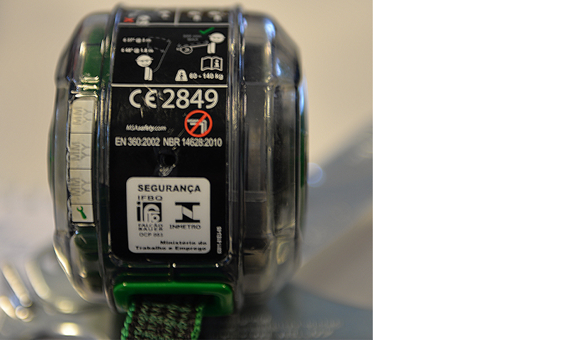 Nærbilde av svart og grønn fallsikring med gjennomsiktig hus og CE2849-merking