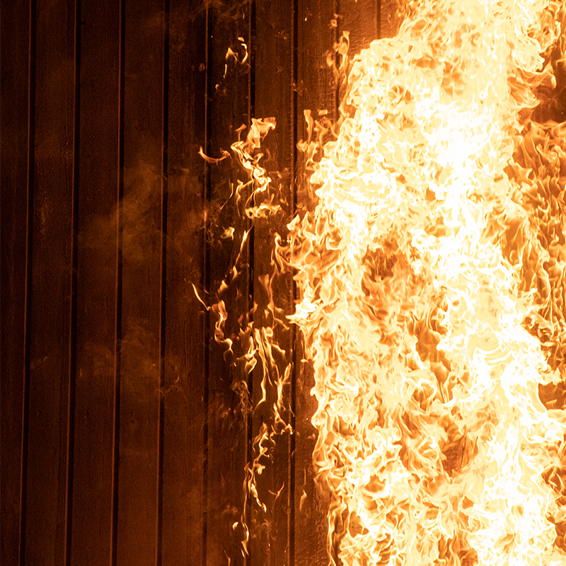 Store gule-oransje flammer mot mørkt, vertikalt trepanel.