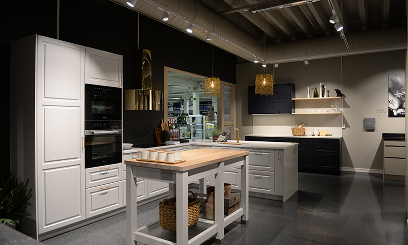Moderne kjøkken i showroom med hvite og svarte skap, trespiseøy og gullpendler