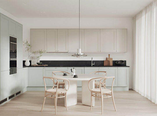 Lyst skandinavisk kjøkken med mintgrønne skap, svart benkeplate, rundt hvitt bord og fire trestoler.