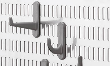 Hvit perforert verktøytavle med grå kroker i ulike former montert i rader.